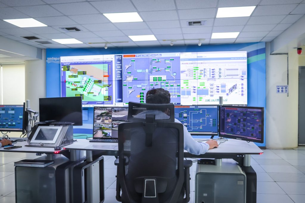 Operador trabalha em uma moderna sala de controle com equipamentos tecnológicos.