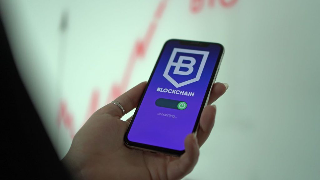 Mão segurando um smartphone com a tela de uma carteira digital de criptomoedas baseada em blockchain