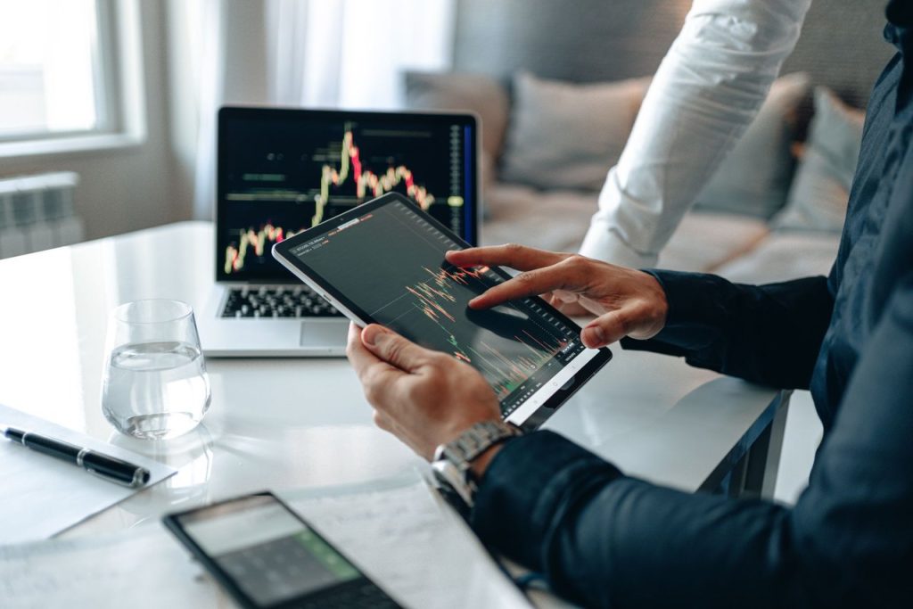 Dois profissionais analisam tendências de mercado usando um tablet e um laptop em um escritório moderno.